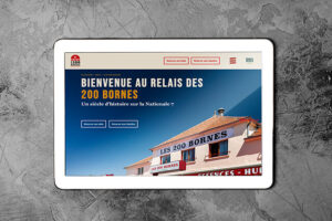 Tablette graphique allumée montrant le site de LE RELAIS DES 200 BORNES, sur un fond en pierre gris.