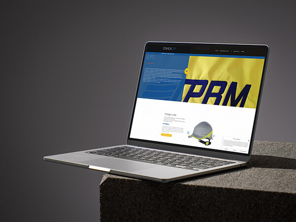 MasBook allumé montrant le site de STARCK UP, sur un bloc de pierre.