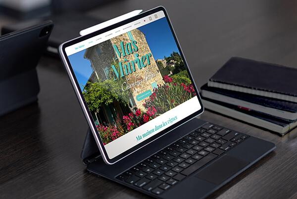 Tablette digitale allumée montrant le site de MAS MÛRIER, dans un bureau.
