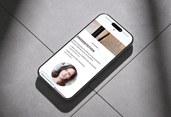 Téléphone allumé montrant le site d'une avocate, sur un carrelage gris.